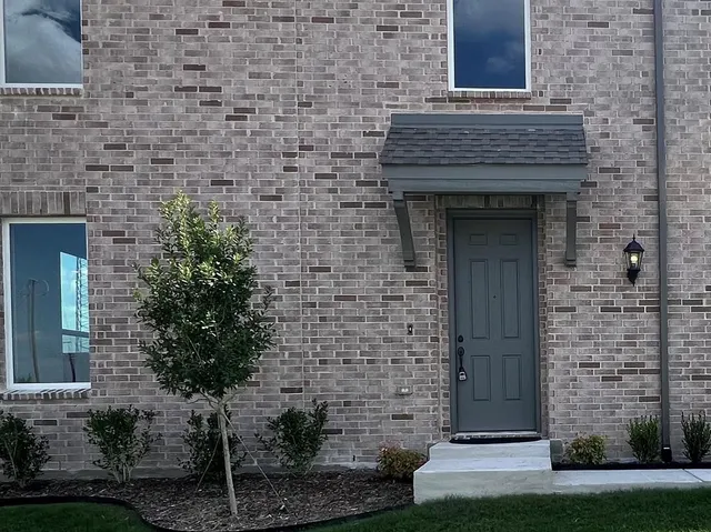 a front view of a brick building with a yard