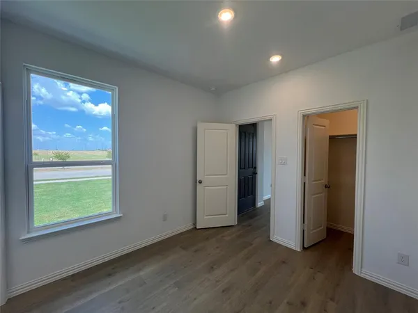 a view of empty room with window and wooden floor