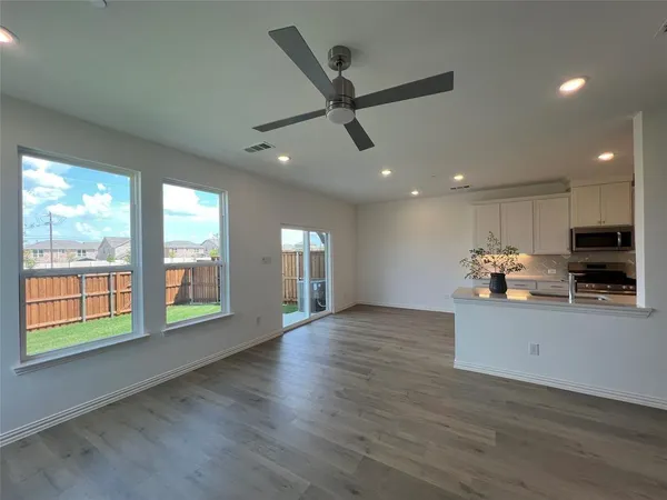a view of an empty room with a window and wooden floor
