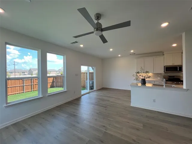 a view of an empty room with a window and wooden floor