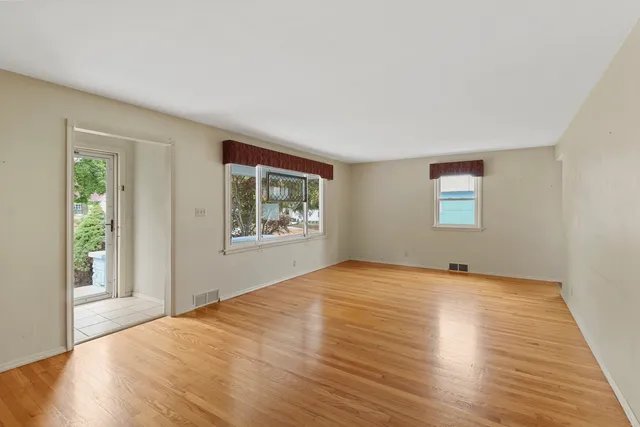 a view of an empty room with window and wooden floor