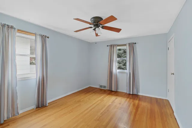 a view of empty room with wooden floor and ceiling fan