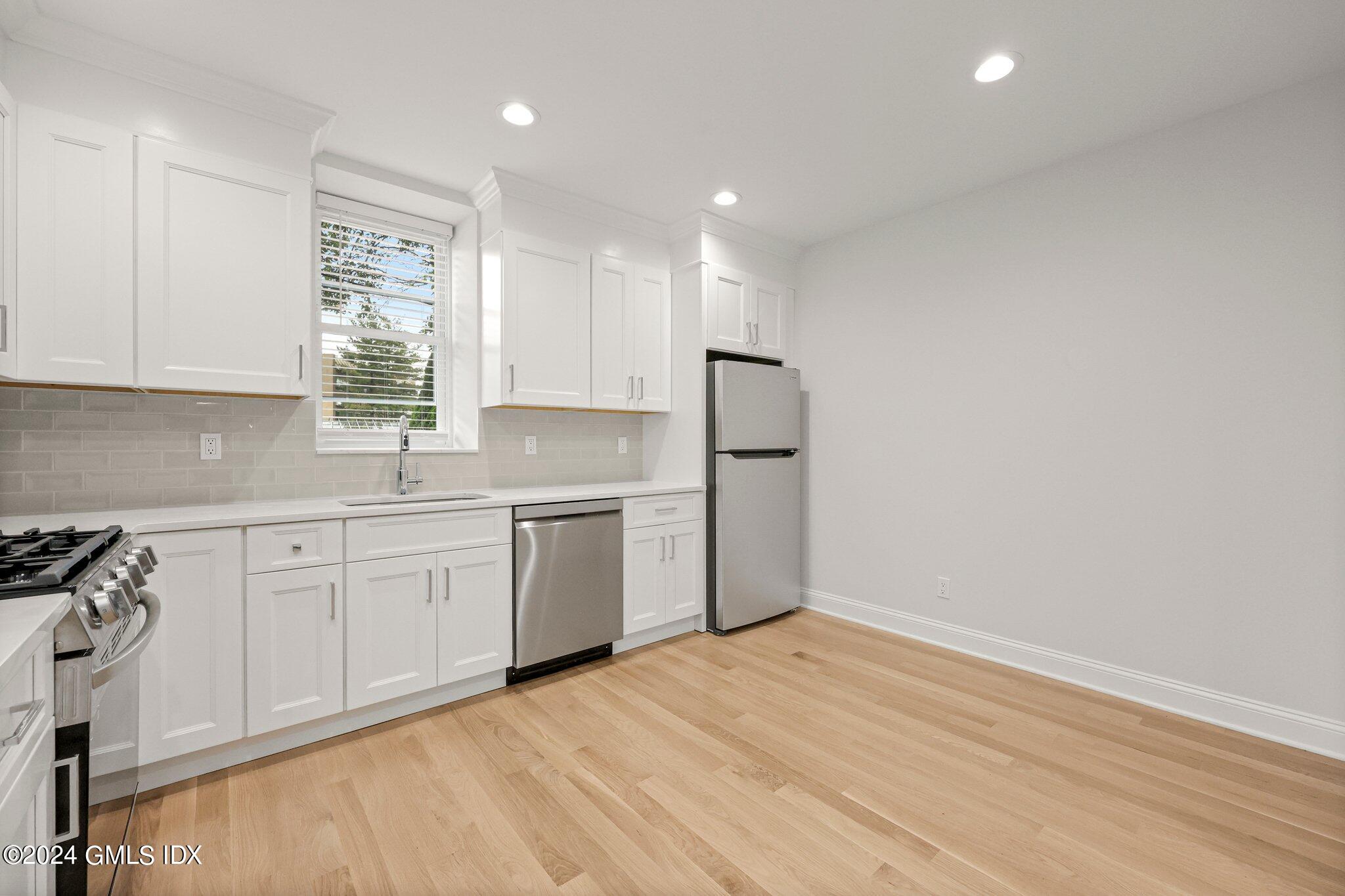 36 Arch Street, Unit 1A Greenwich, CT 06830 - Photo 11 of 19 a kitchen with granite countertop white cabinets and white appliances
