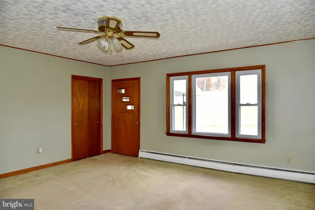 an empty room with chandelier fan and windows