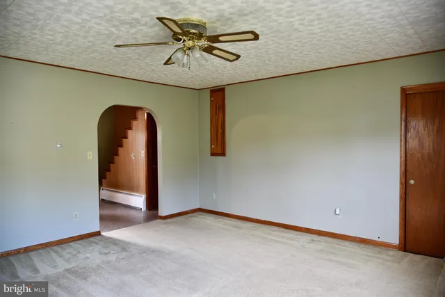 an empty room with a chandelier fan and closet