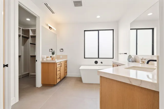 a large white bathroom with double vanity sink a mirror and a bathtub
