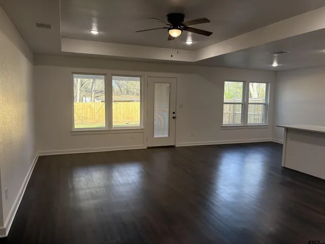 an empty room with wooden floor and windows