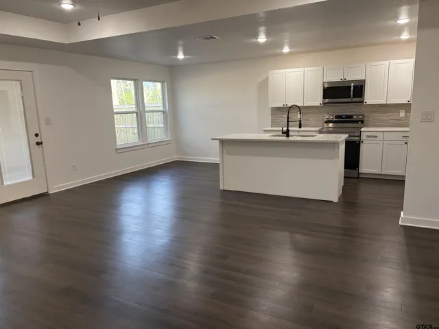 a view of kitchen with stainless steel appliances granite countertop a stove a sink dishwasher and a microwave with wooden floor