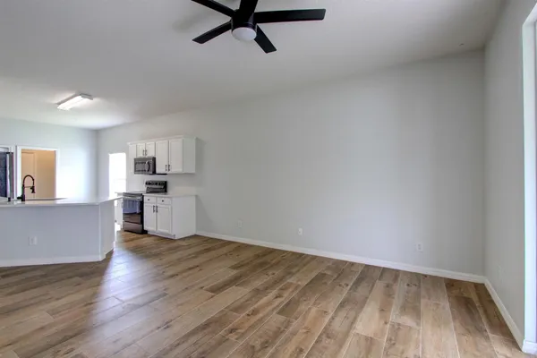 a view of kitchen and empty room with wooden floor