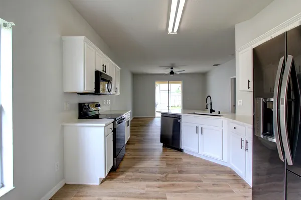 a large kitchen with stainless steel appliances a refrigerator stove top oven and sink