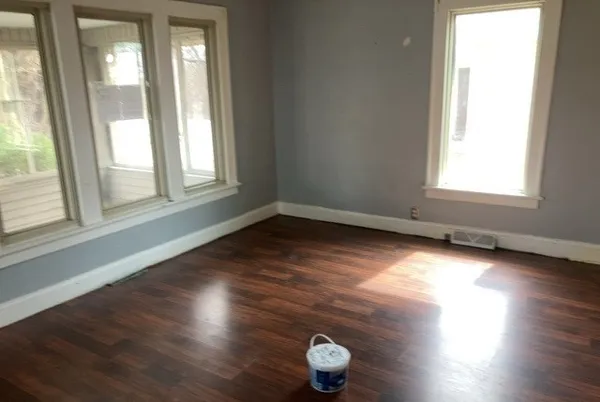 an empty room with wooden floor and windows