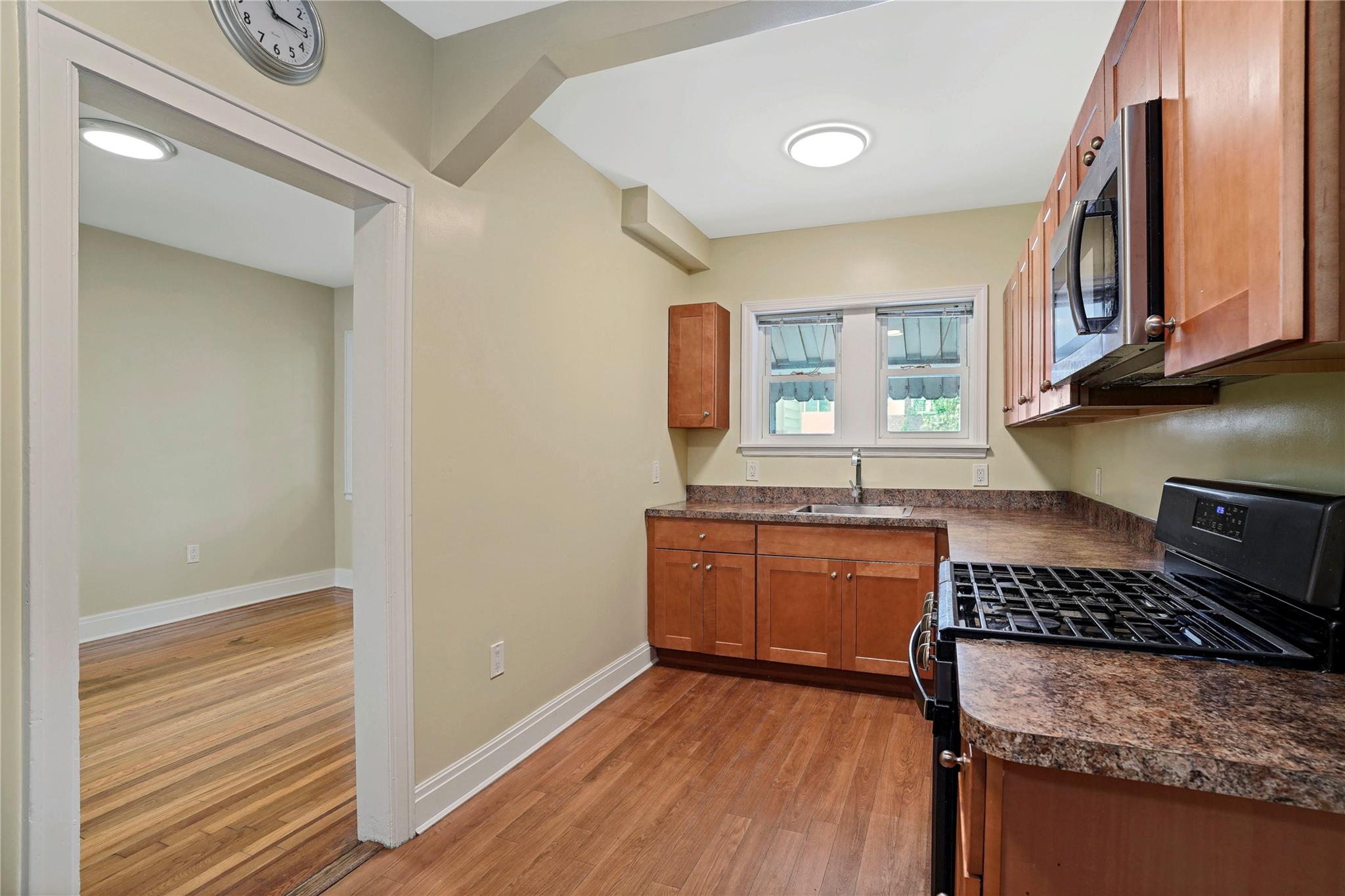 64-18 84th Place Queens, NY 11379 - Photo 13 of 35 a kitchen with granite countertop wooden cabinets and a stove top oven