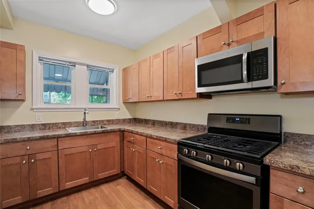 a kitchen with stainless steel appliances white cabinets granite counter tops and a window
