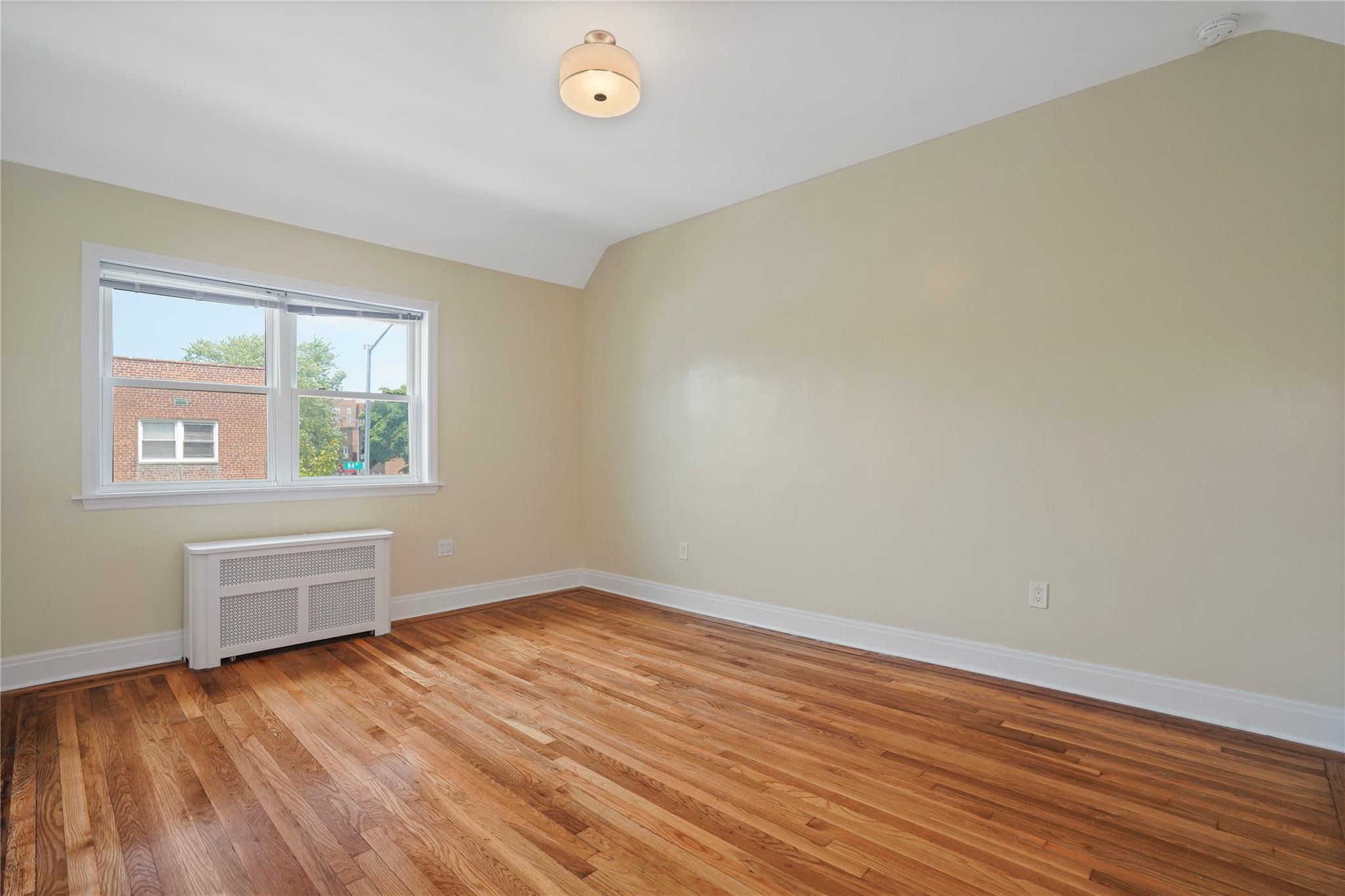 64-18 84th Place Queens, NY 11379 - Photo 26 of 35 an empty room with wooden floor and windows