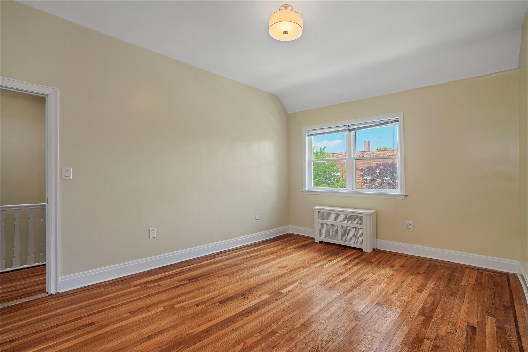 64-18 84th Place Queens, NY 11379 - Photo 28 of 35 an empty room with wooden floor and windows