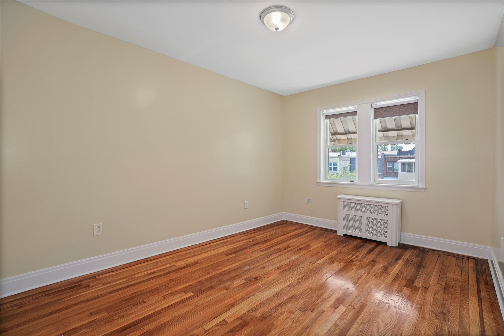 64-18 84th Place Queens, NY 11379 - Photo 29 of 35 an empty room with wooden floor and windows