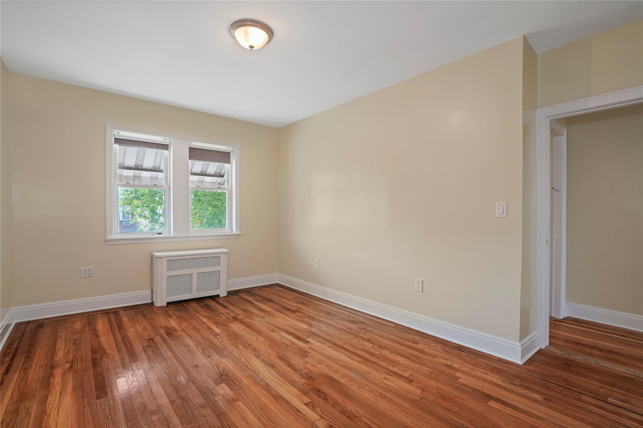 64-18 84th Place Queens, NY 11379 - Photo 30 of 35 an empty room with wooden floor and windows
