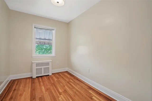 a view of a yard in front of a brick house with plants and large tree