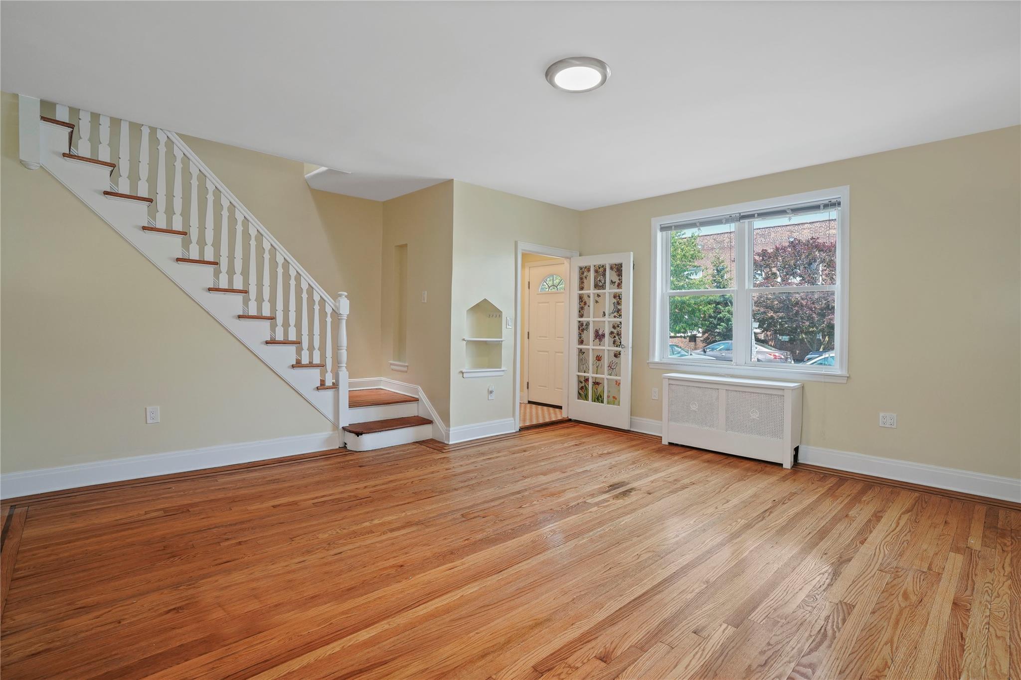 64-18 84th Place Queens, NY 11379 - Photo 5 of 35 a view of an empty room with wooden floor and a window