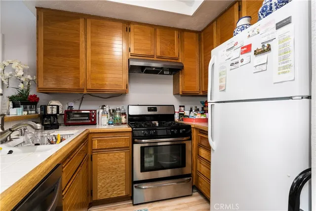a kitchen with granite countertop a refrigerator a stove a sink and dishwasher