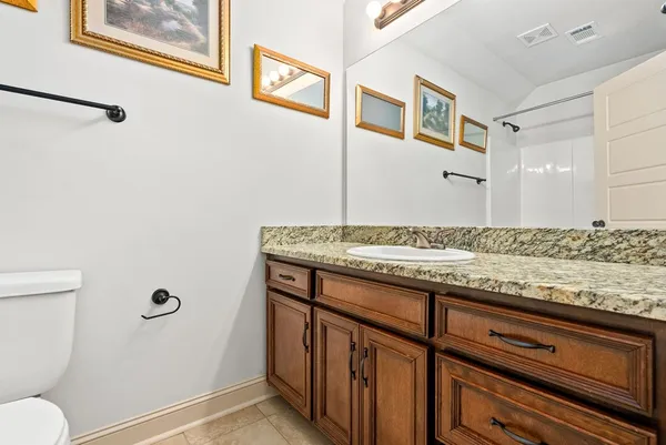 a bathroom with a granite countertop sink and a toilet