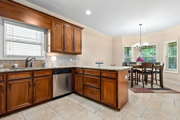 a kitchen with stainless steel appliances granite countertop wooden cabinets a dining table and chairs