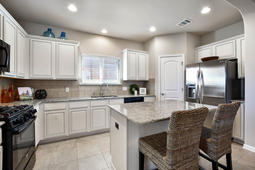3451 Mayfield Ranch Boulevard, Unit 216 Round Rock, TX 78681 - Photo 12 of 33 a kitchen with stainless steel appliances granite countertop a stove a sink dishwasher a refrigerator and white cabinets with wooden floor