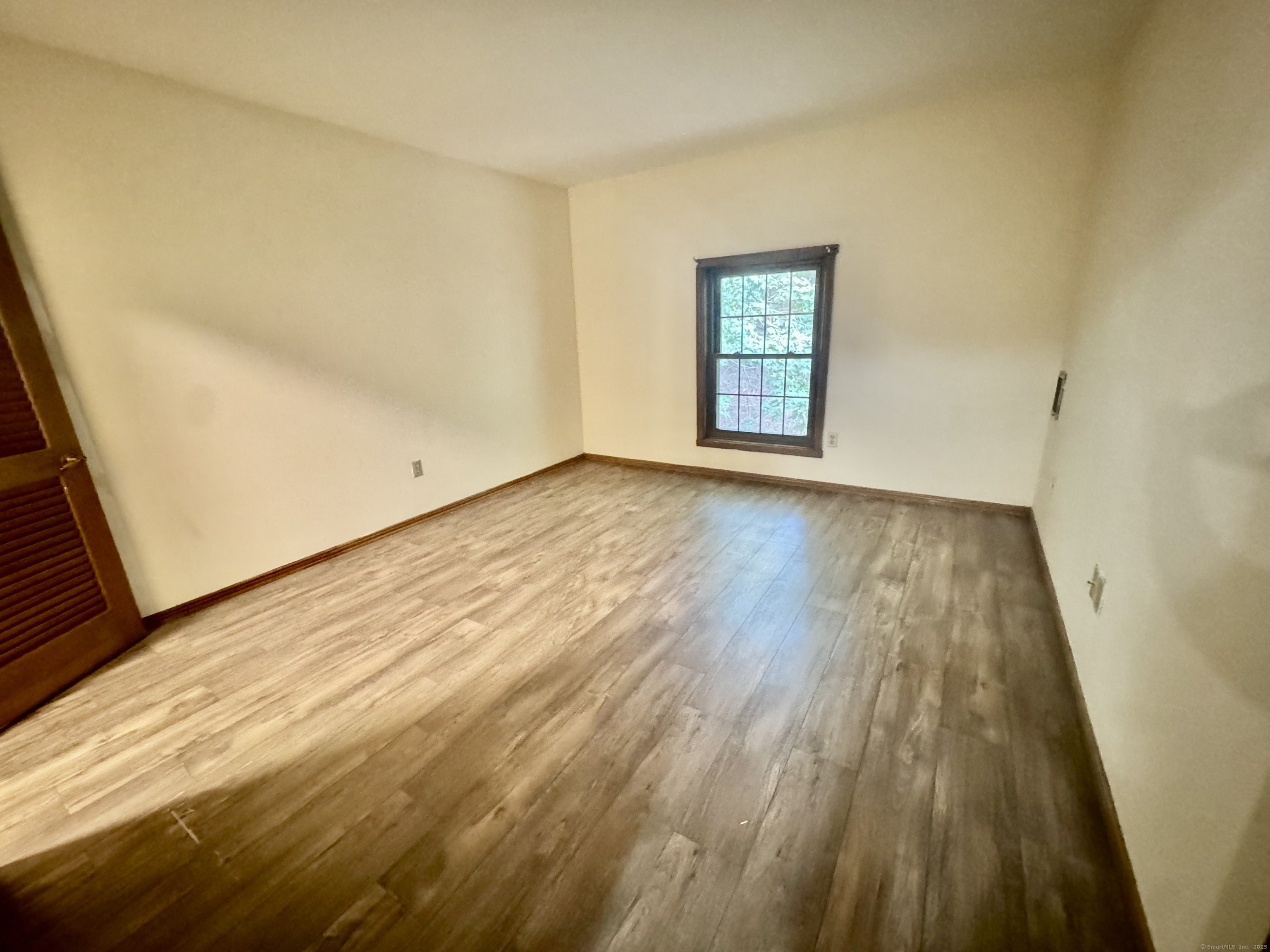 24 West Road, Unit 44 Ellington, CT 06029 - Photo 6 of 9 a view of an empty room with wooden floor and a window