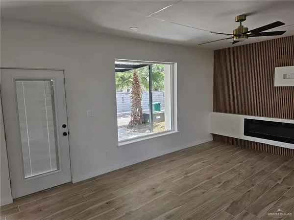 a view of an empty room with wooden floor and a window