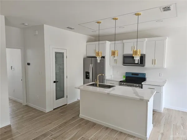 a kitchen with kitchen island a counter top space a sink a refrigerator and a wooden floor