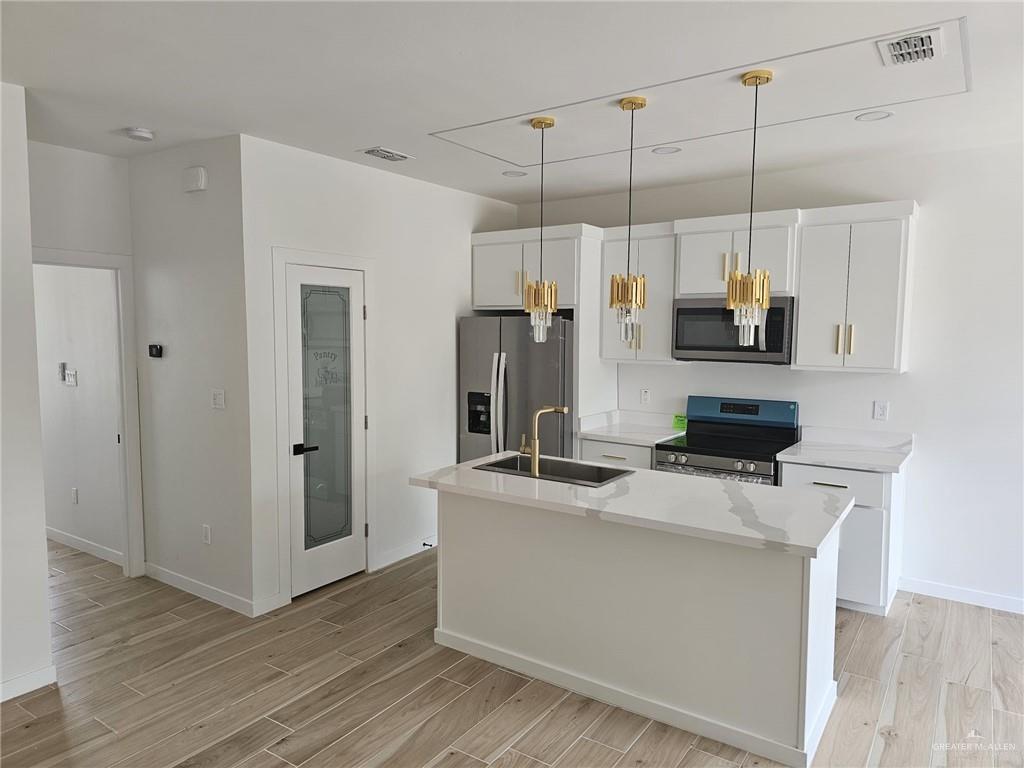 5500 North Crown Point Pharr, TX 78577 - Photo 10 of 39 a kitchen with kitchen island a counter top space a sink a refrigerator and a wooden floor