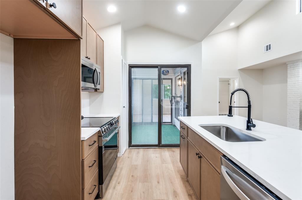 17490 Meandering Way, Unit 2202 Dallas, TX 75252 - Photo 18 of 24 Contemporary kitchen featuring wood-finish cabinetry, stainless steel appliances, and light countertops