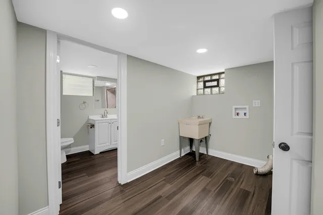 a view of a hallway with wooden floor and a bathroom