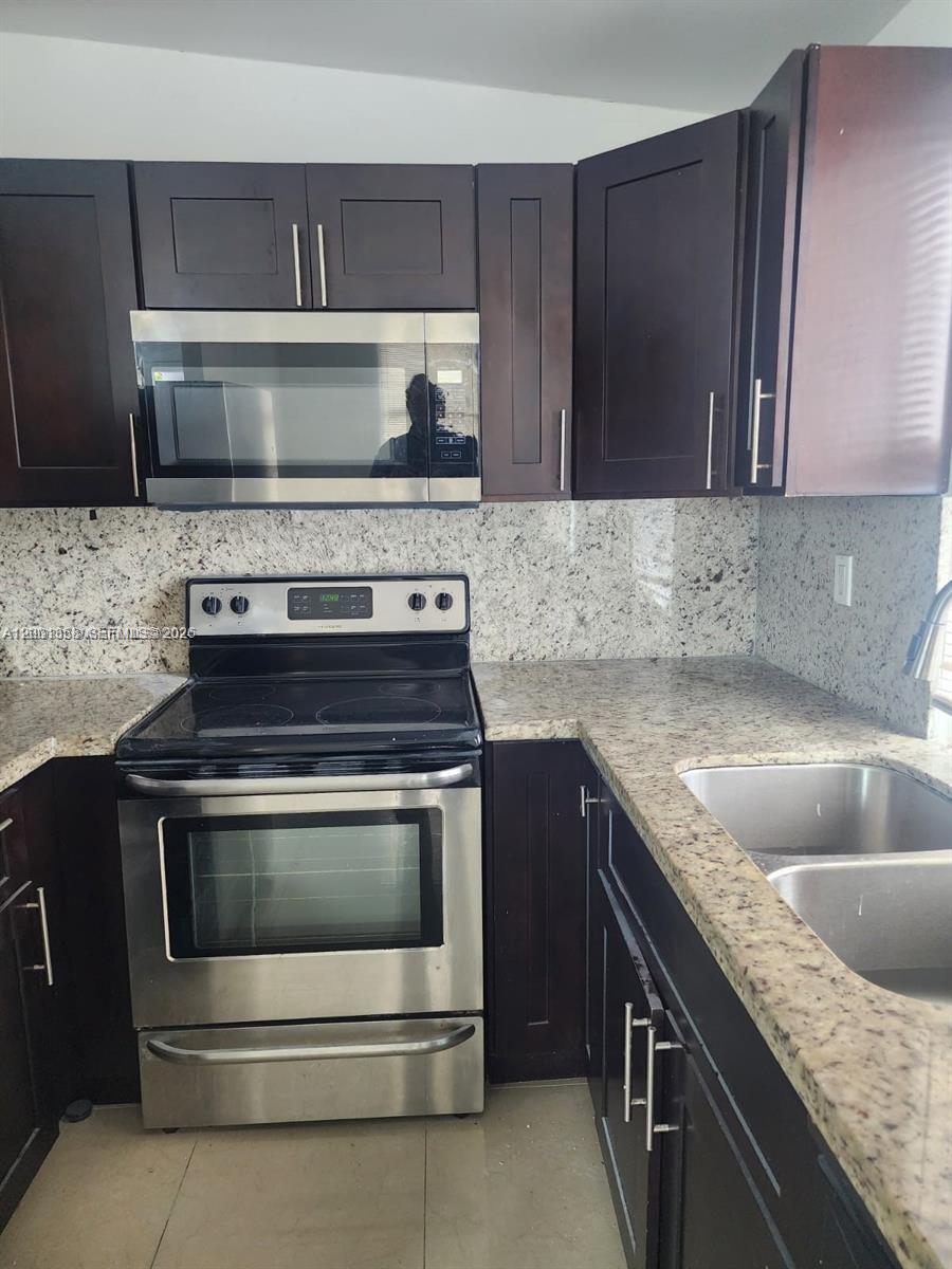 1726 Southwest 25th Avenue, Unit 1 Miami, FL 33145 - Photo 4 of 14 a kitchen with granite countertop a sink stove and cabinets