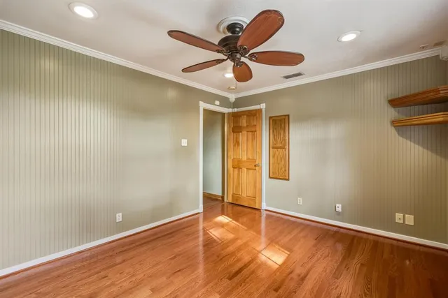 an empty room with wooden floor and a ceiling fan