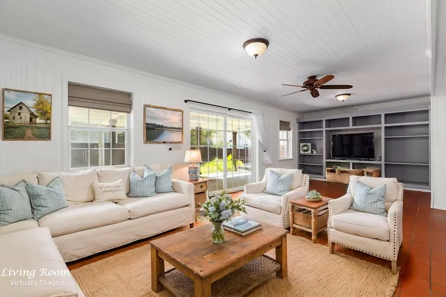 a living room with furniture ceiling fan and a large window