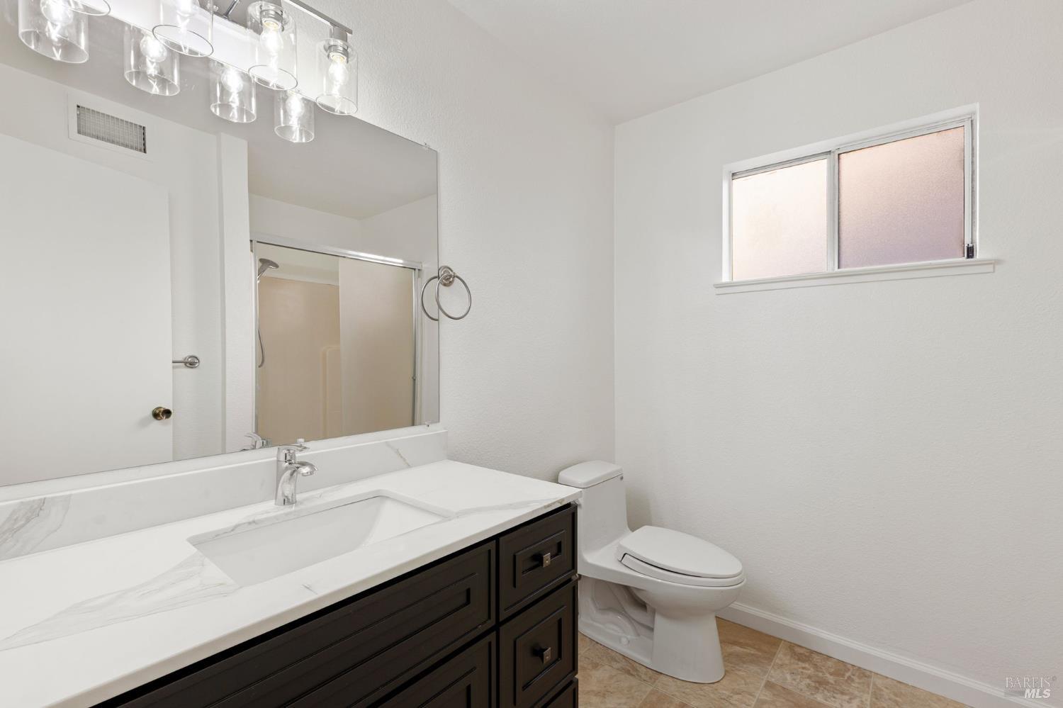 570 Berkeley Way Fairfield, CA 94533 - Photo 24 of 34 a bathroom with a granite countertop sink a toilet and a mirror