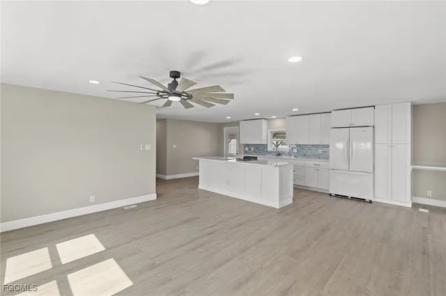 a view of an empty room and kitchen with wooden floor and cabinet