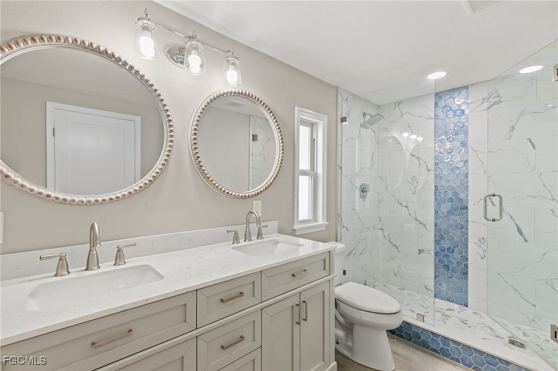 57 San Remo Circle Naples, FL 34112 - Photo 21 of 28 a bathroom with a toilet a sink a mirror and shower