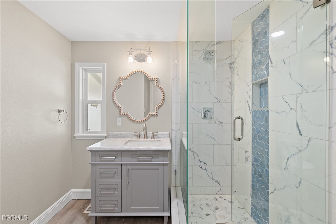 57 San Remo Circle Naples, FL 34112 - Photo 24 of 28 a bathroom with a granite countertop sink a mirror and shower