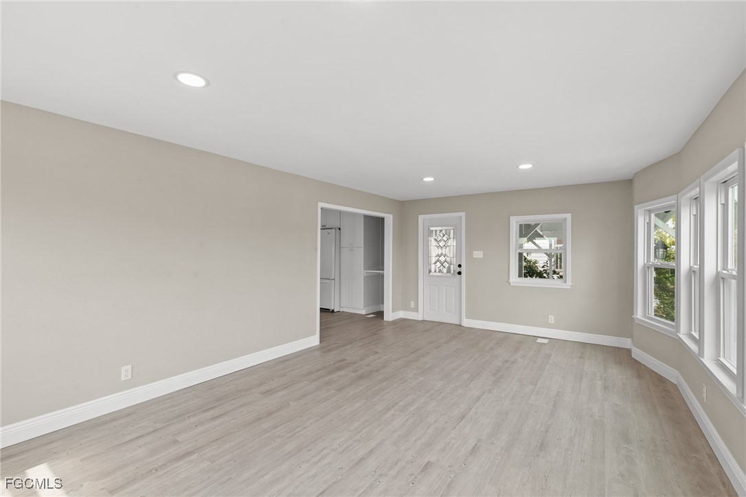 57 San Remo Circle Naples, FL 34112 - Photo 7 of 28 an empty room with wooden floor and windows