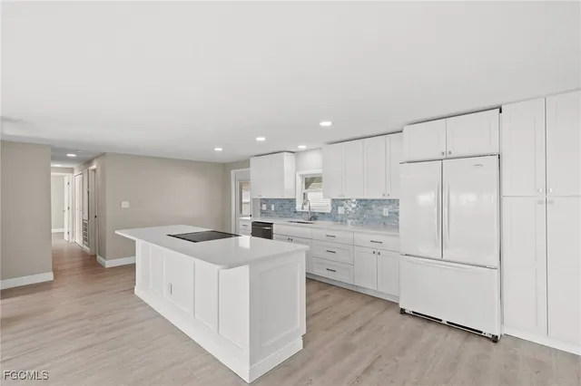 a kitchen with kitchen island sink stove and white cabinets with wooden floor