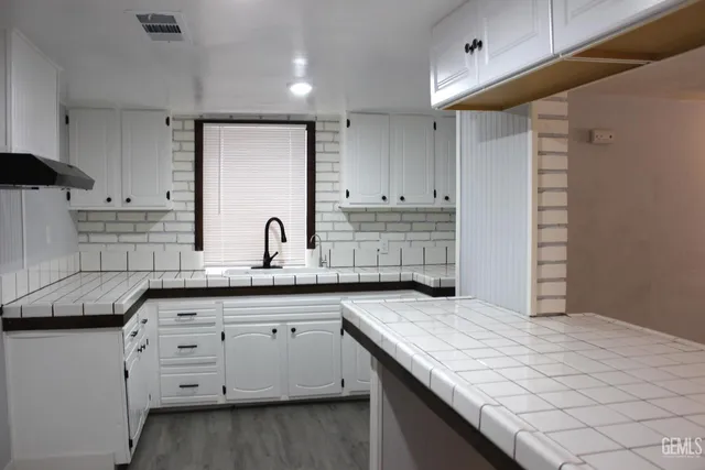 a kitchen with granite countertop white cabinets and sink