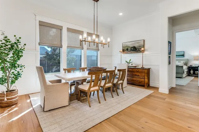a dining room with wooden floor a chandelier a glass table and chairs