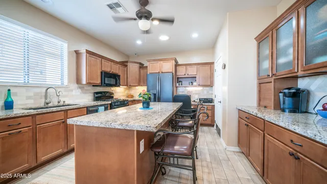 a kitchen with granite countertop kitchen island stainless steel appliances a sink stove and refrigerator