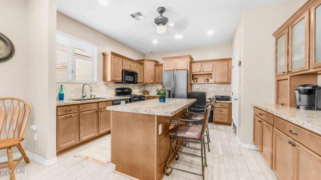 a kitchen with stainless steel appliances granite countertop a stove top oven a sink dishwasher a dining table and chairs with wooden floor