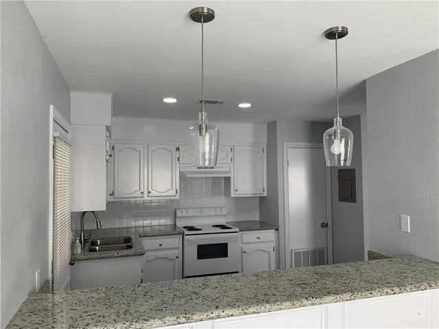 a kitchen with stainless steel appliances granite countertop a refrigerator a sink a stove and oven