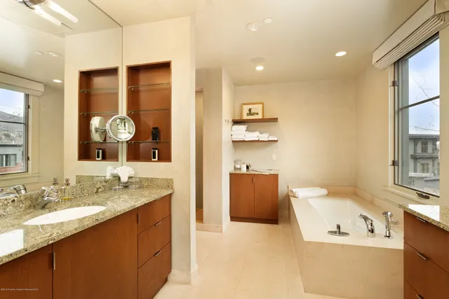 a bathroom with a granite countertop sink a mirror and a bathtub