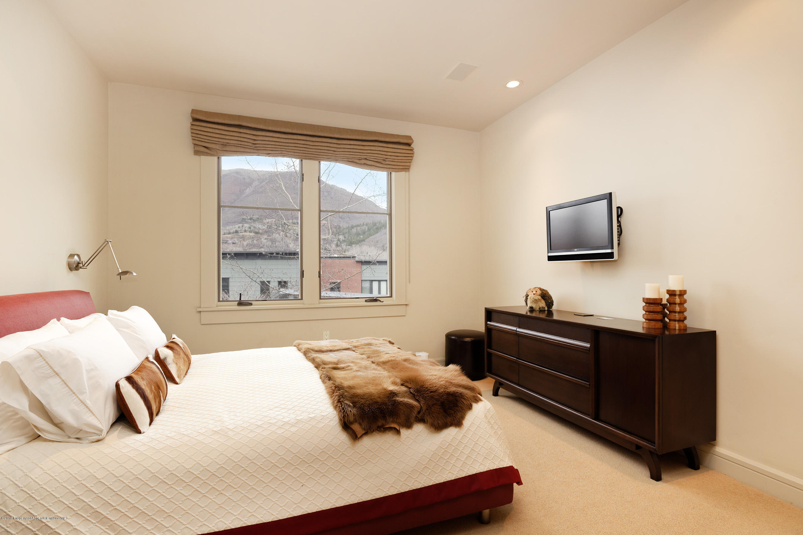 102 Founders Place, Unit 301 Aspen, CO 81611 - Photo 15 of 28 a bedroom with a bed and a flat tv screen on dresser