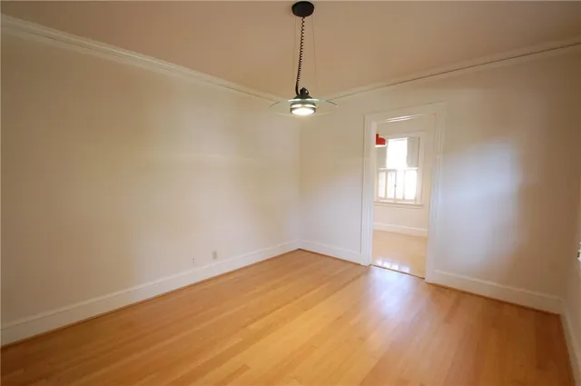 an empty room with wooden floor ceiling fan and windows